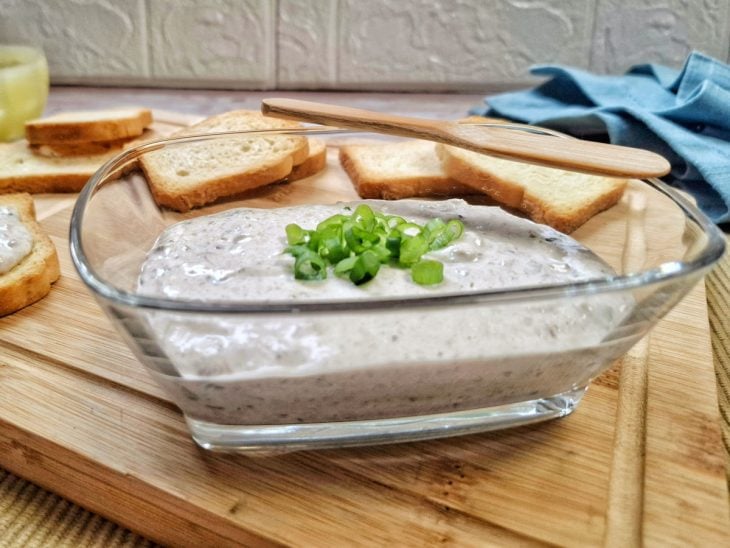 Patê de sardinha servido em um recipiente de vidro e finalizado com cebolinhas.