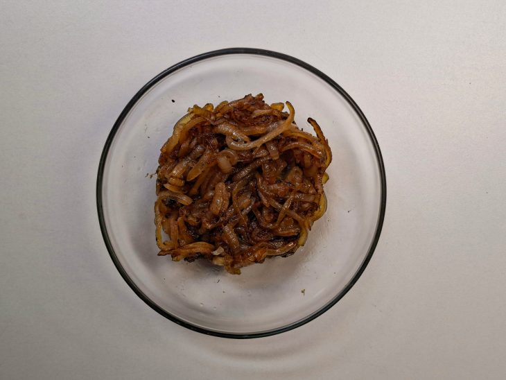 Cebola caramelizada reservada num recipiente redondo de vidro.