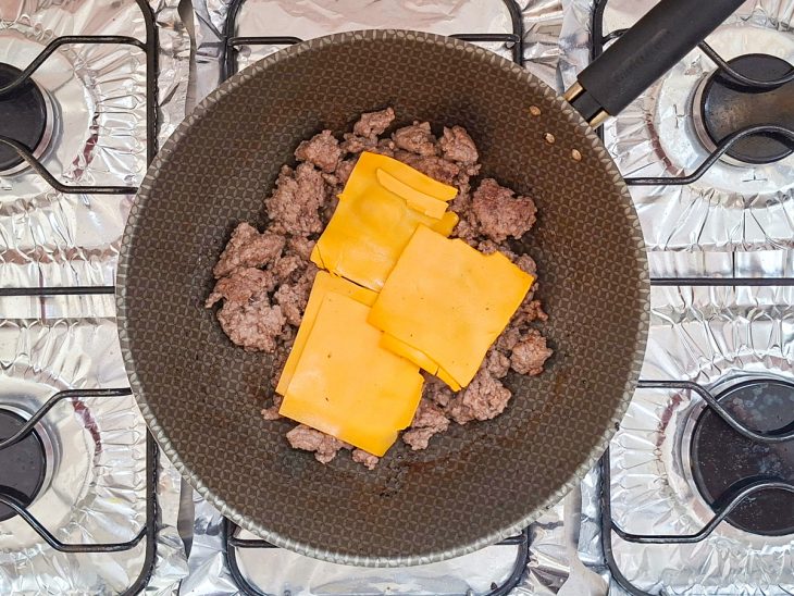 Queijo colocado sobre a carne na frigideira.