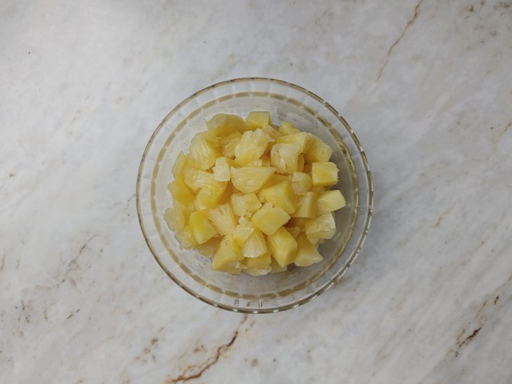 Abacaxi descascado e cortado em cubos cozinhando com açúcar.