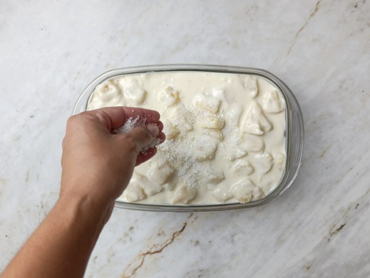 Montagem do pavê no refratário com camadas alternadas de creme e bolacha.