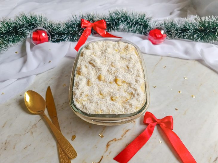 Pavê de abacaxi com bolacha servido na travessa com decoração ao fundo.