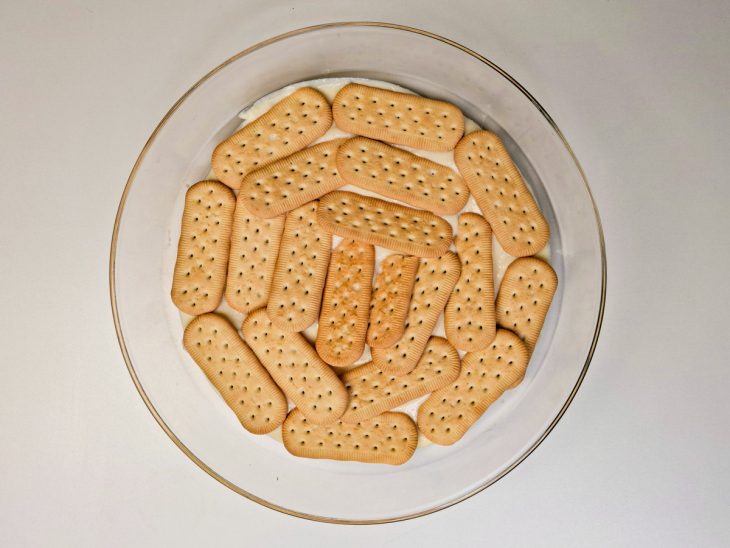 Camada de bolacha sobre o creme, na travessa.