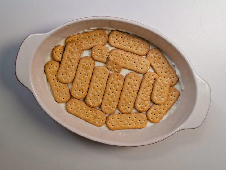 Camada de biscoito sobre o creme na travessa.