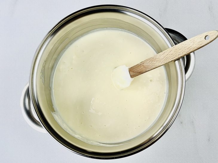 Leite condensado, creme de leite, leite em pó e manteiga misturados em uma panela.