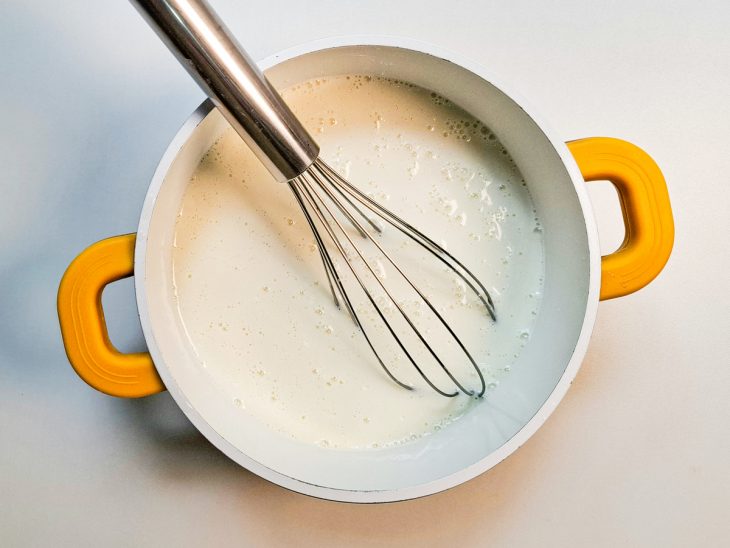 Numa panela, o leite, o leite condensado, o creme de leite e o amido de milho adicionados.