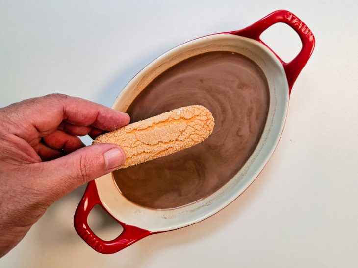 Numa tigela com leite e achocolatado, as bolachas sendo molhadas.