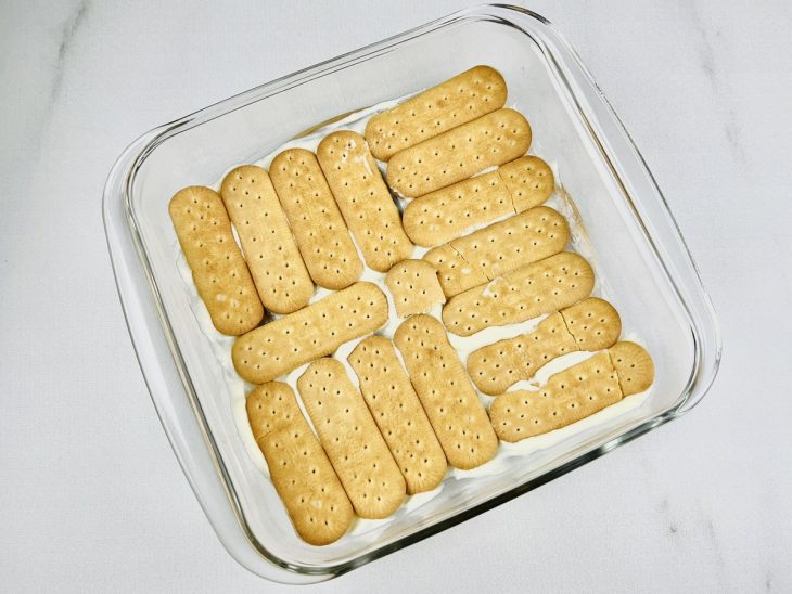 No refratário, uma camada das bolachas regadas no leite.