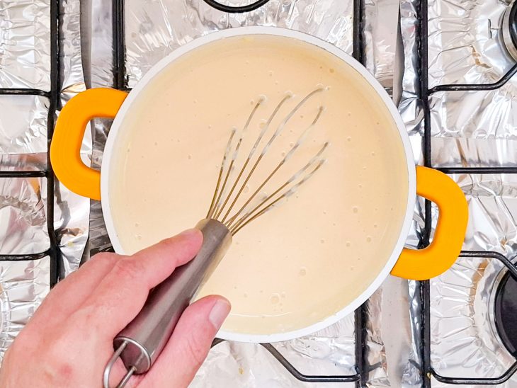 Panela no fogo, mistura sendo mexida com fouet.
