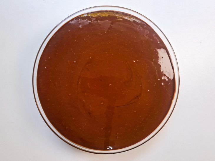 Na travessa, o chocolate derretido formando uma camada sobre o pavê.