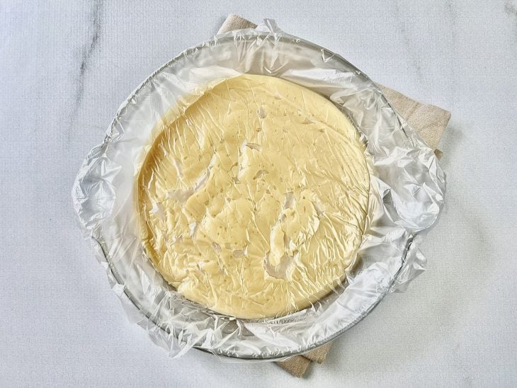 Brigadeiro de chocolate branco em um prato de vidro coberto com plástico.
