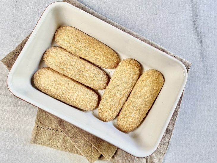 Travessa com uma camada de biscoitos cobrindo o fundo.