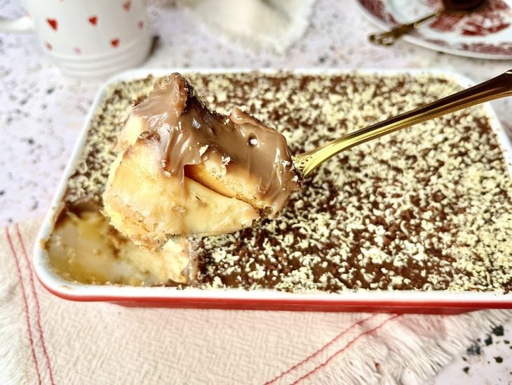 Pavê de chocolate preto e branco pronto para consumo e uma porção dele em uma colher.
