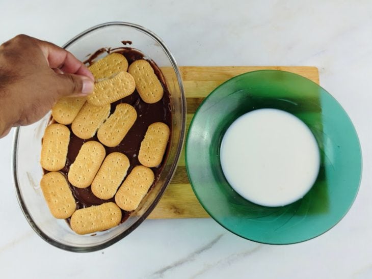 Uma travessa com uma camada de creme de chocolate e uma de bolacha.