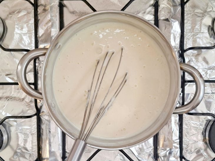 Uma panela com creme de leite sendo misturado no fogão.
