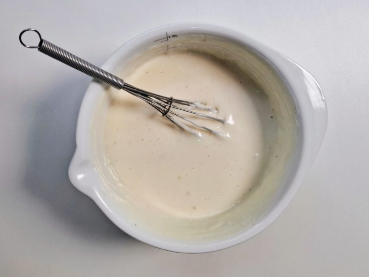 Uma tigela com fouet e o creme branco pronto.