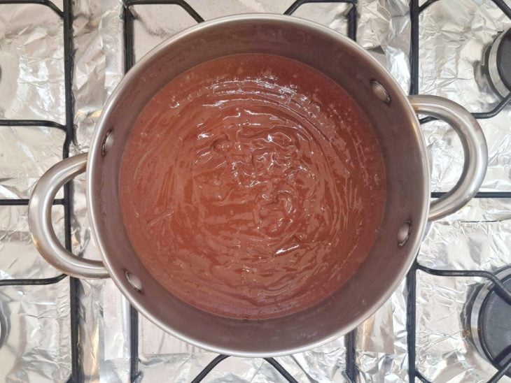 Uma panela com o creme branco misturado com chocolate em pó.