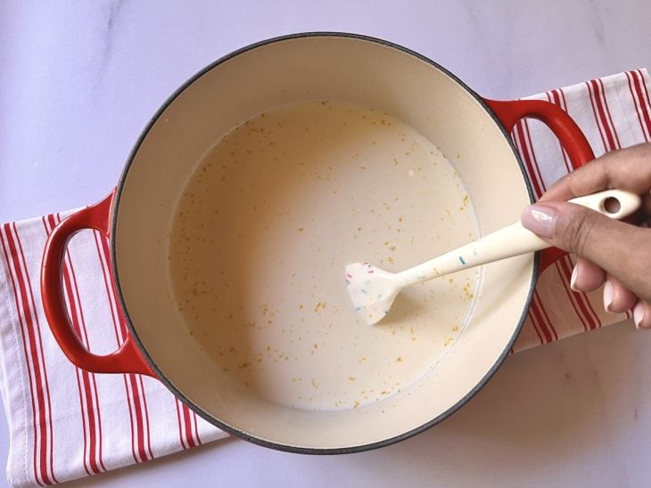 Uma panela contendo a mistura de leite condensado, amido de milho, gema, leite, creme de leite e essência de baunilha.