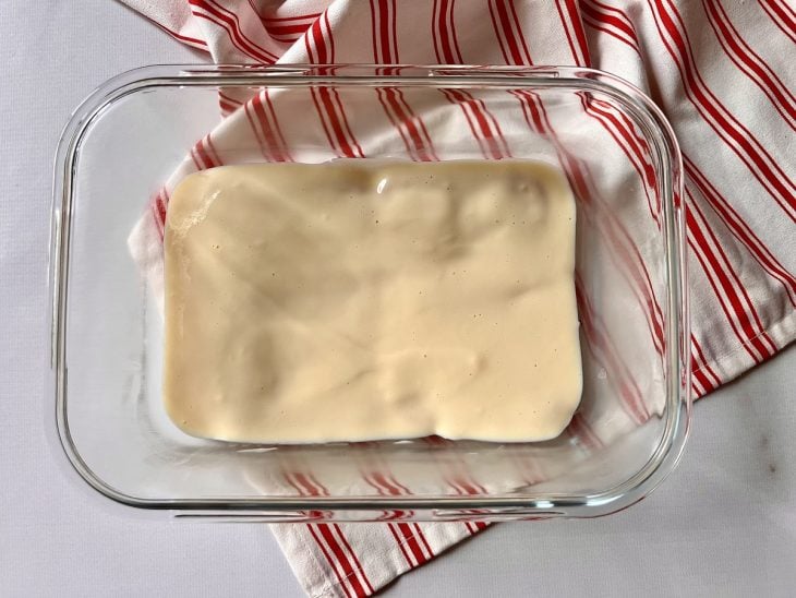 Um refratário forrado com bolachas maizenas cobertas com creme branco.