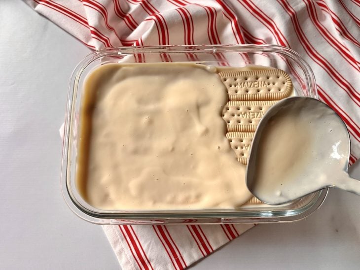 Um refratário forrado com bolachas maizenas cobertas com creme branco.