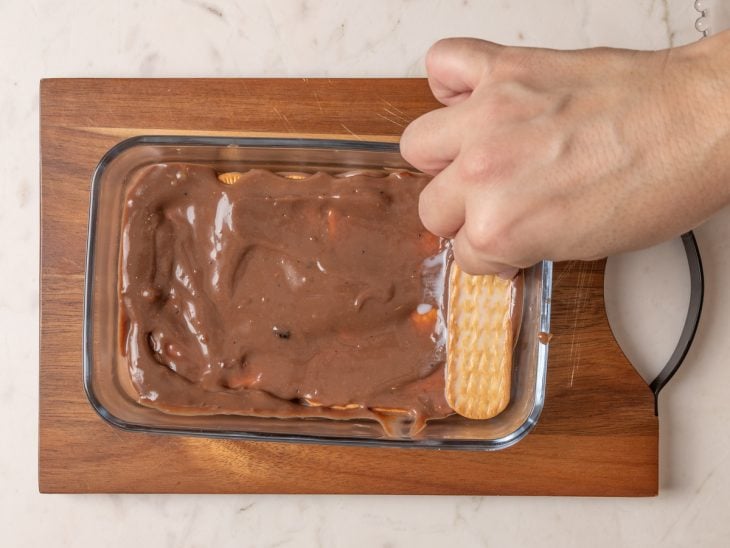 Bolacha umedecida acomodada sobre a camada de creme de chocolate.