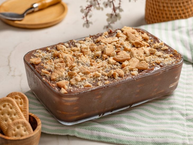 Pavê de chocolate simples pronto para consumo, finalizado com bolachas esfareladas e salpicadas.