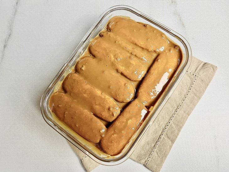 Uma travessa com uma camada de bolachas e uma de recheio de doce de leite.