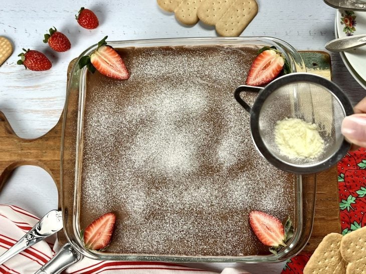 Uma travessa contendo pavê de leite Ninho com chocolate e morango.