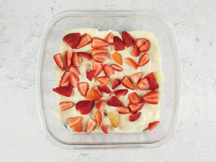 Pavê com uma das camadas prontas, creme, biscoito e morangos.