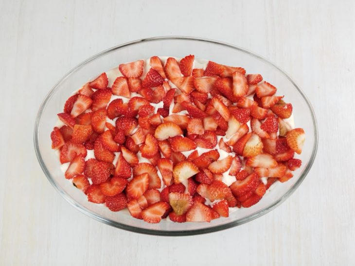 Morangos picados despejados sobre o creme.