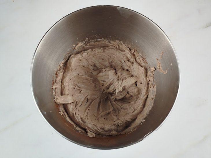 Doce de leite, leite em pó e chocolate em pó adicionados ao recipiente da batedeira.