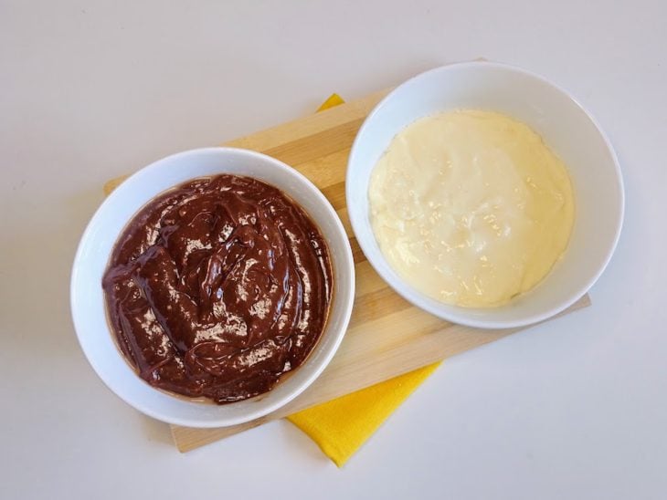 Dois recipientes contendo creme branco doce e no outro creme de chocolate.