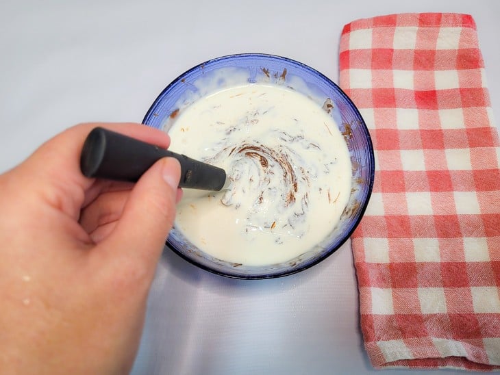 Um recipiente com a mistura de chocolate derretido e creme de leite.