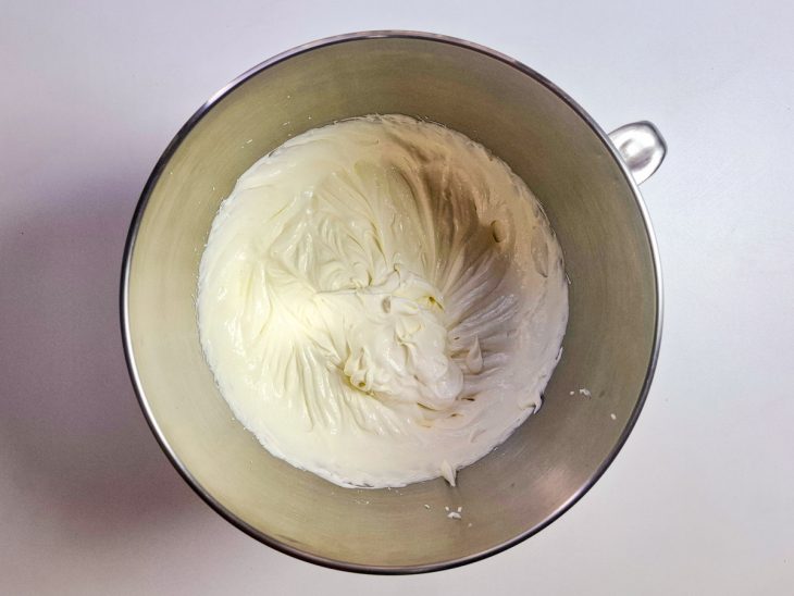 Nata, creme de leite e leite condensado batidos na tigela da batedeira.