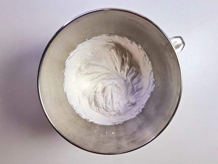 Creme de leite fresco batido com açúcar no recipiente da batedeira.
