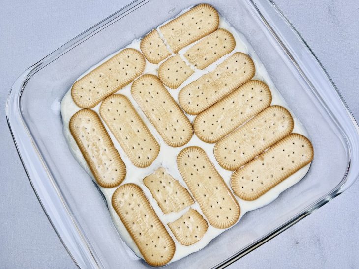 Bolachas umedecidas pela calda de pêssego sobre a camada de creme.