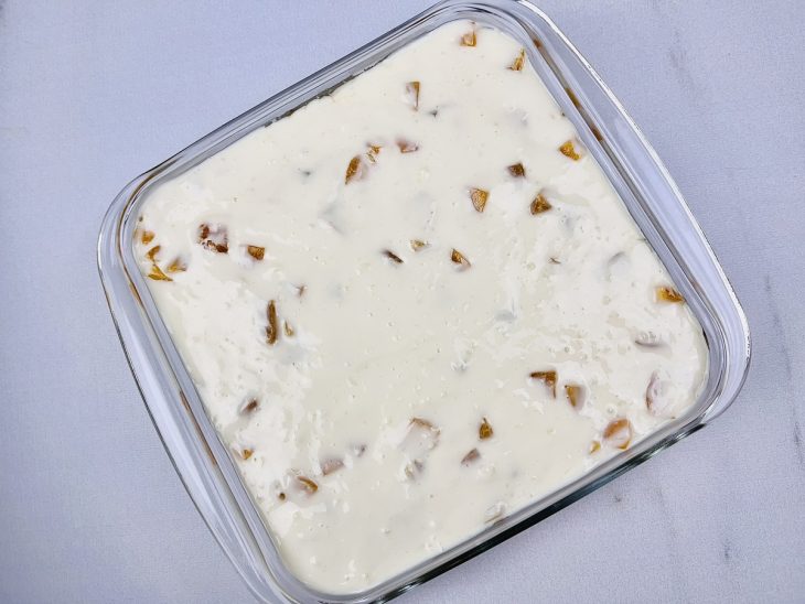 Camadas de creme, bolacha e abacaxi adicionadas ao refratário.