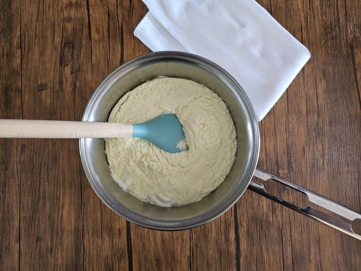 Leite condensado, creme de leite, leite em pó misturados em uma panela.