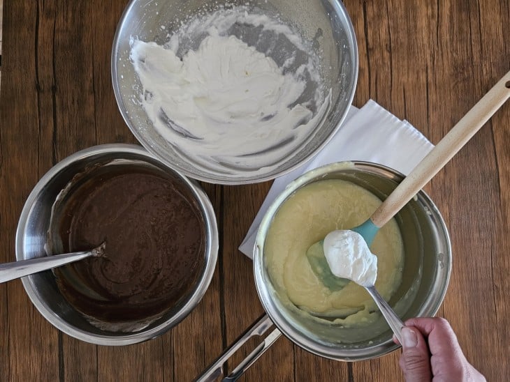 Metade do chantilly sendo colocado no creme e panela com chocolate ao lado.