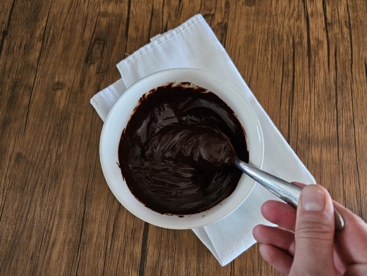 Chocolate em barra e creme de leite sendo misturado.