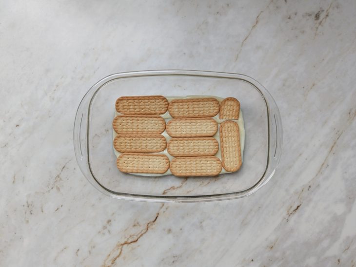 Na travessa, camada do creme e de bolacha.