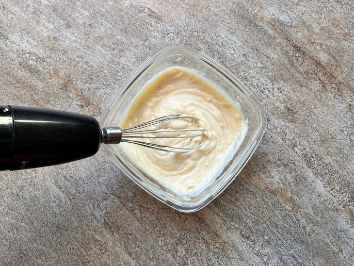 A tigela com a mistura, e um mixer aparecem em cima da mesa.