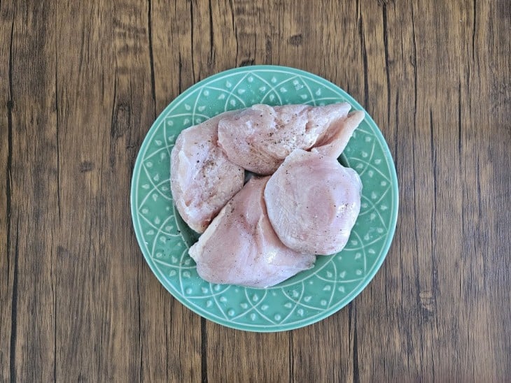 Peitos de frango temperados em um prato.