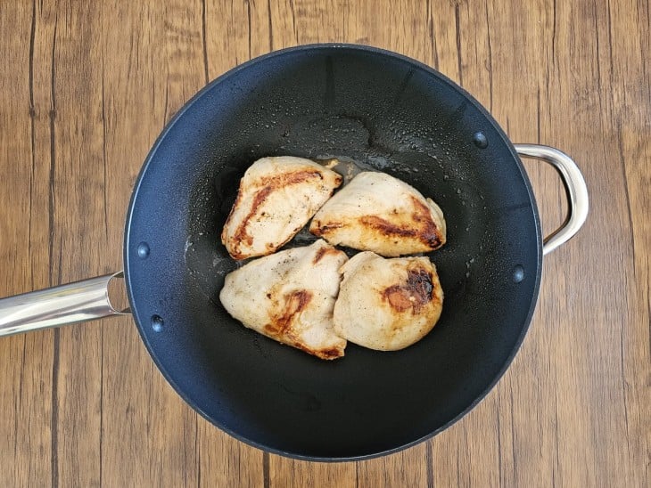 Peitos de frango selados em uma frigideira.