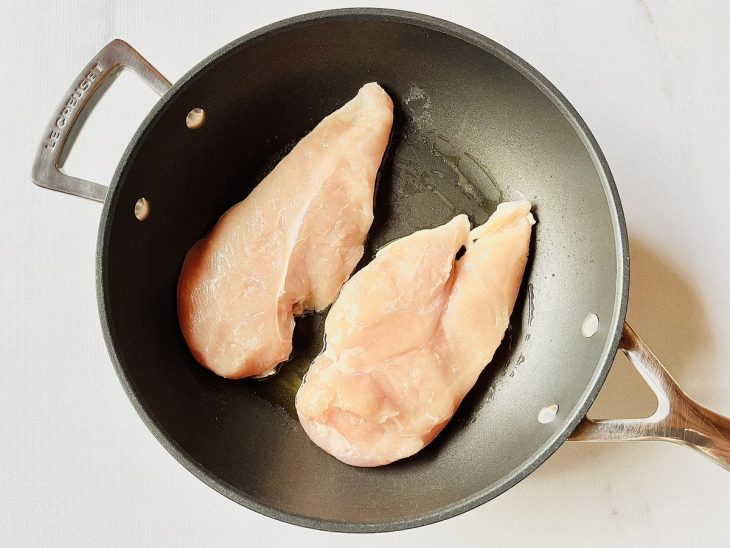 Peitos do frango dispostos numa frigideira.