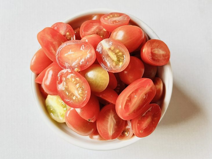 Numa tigela, os tomates cortados ao meio.