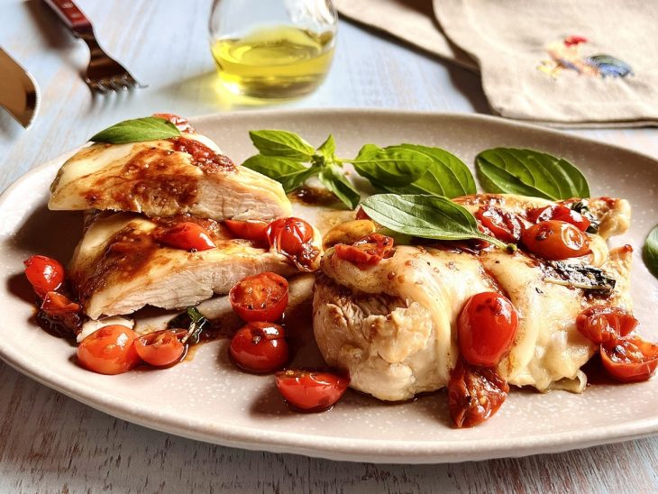 Fil[e de frango cortado e servido em prato, com ramos de manjericão enfeitando.