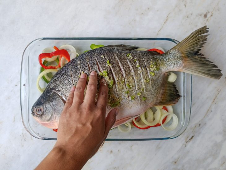 Marinada espalhada por todo o peixe e entre os cortes.