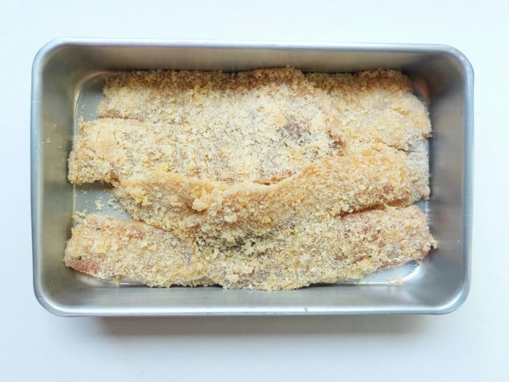 Os filés de peixe empanados em um recipiente.