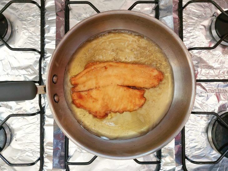 Panela com óleo quente fritando o filé de tilápia.